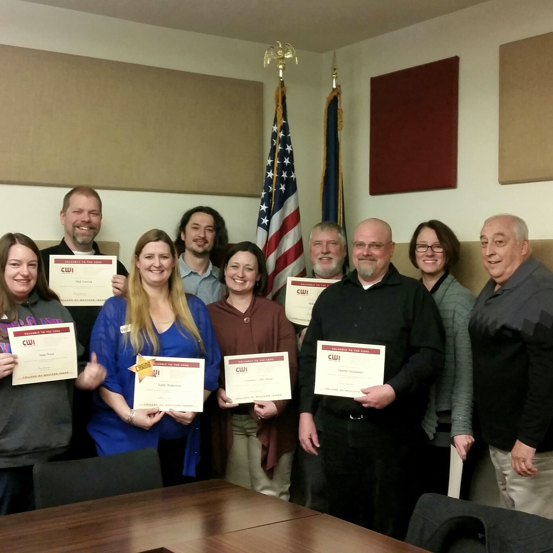 Group of employees with certificates in presidents conference room
