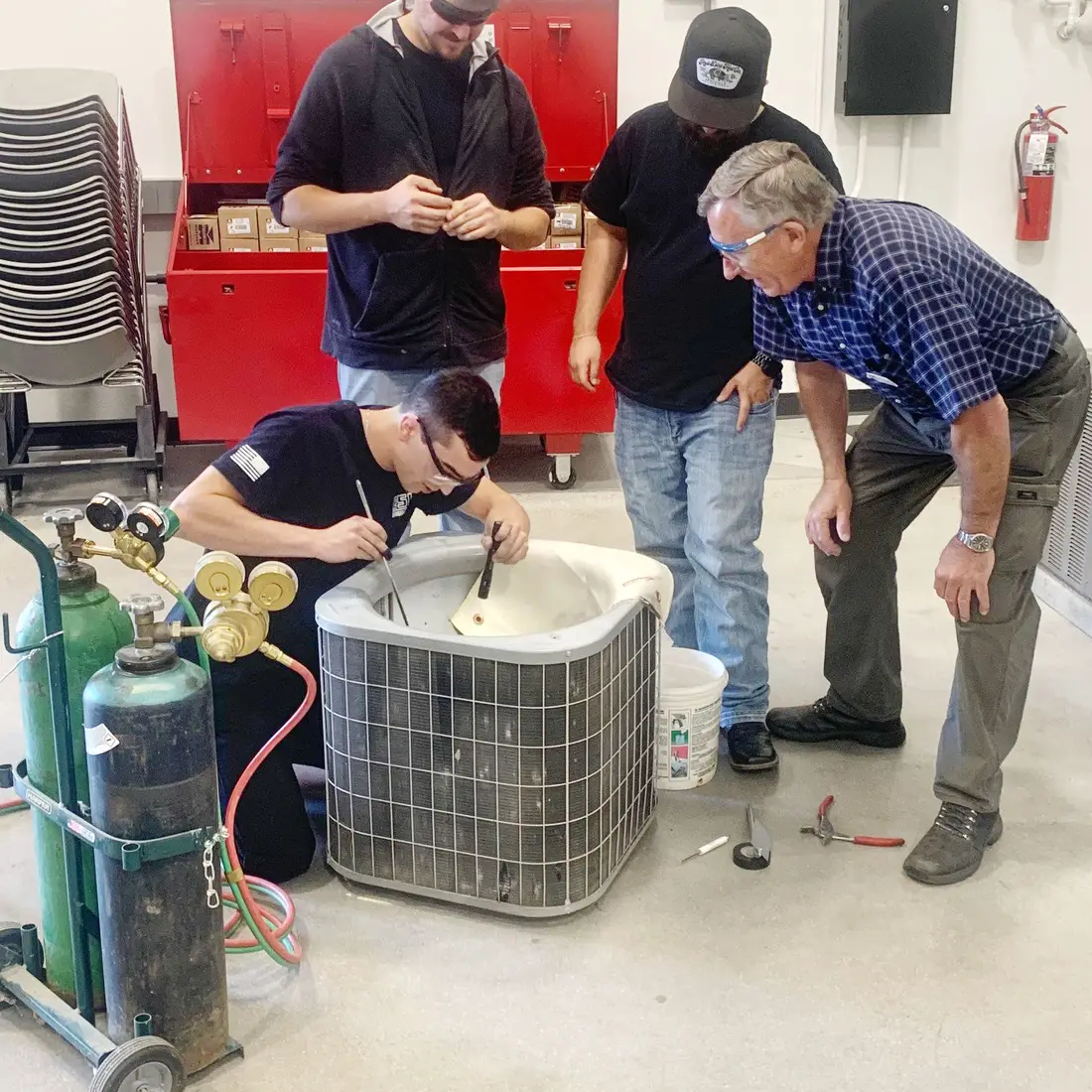 Students learn how to repair an air conditioning unit from an instructor.