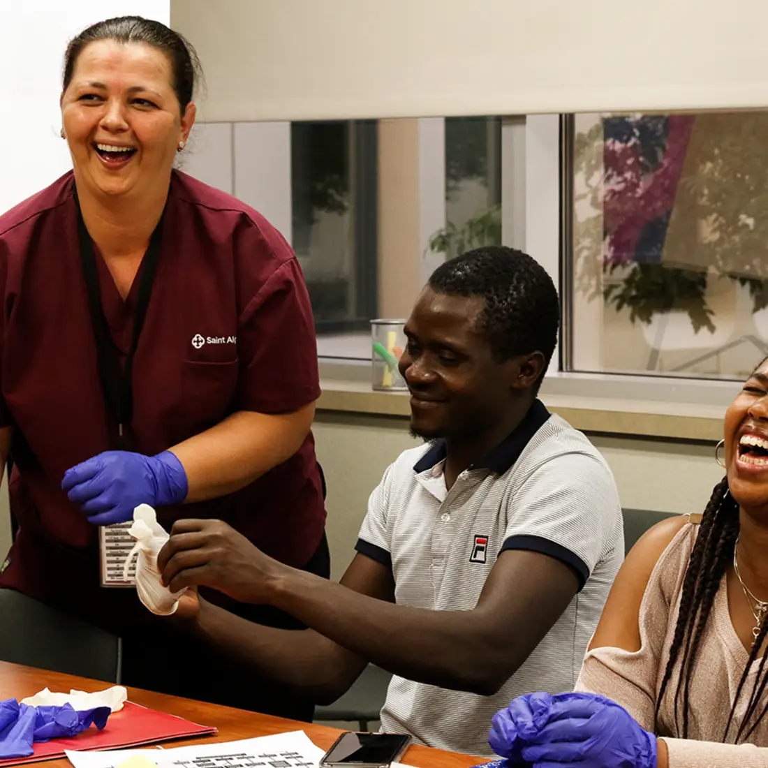 Saint Alphonsus instructor with two happy students learning proper glove techniques