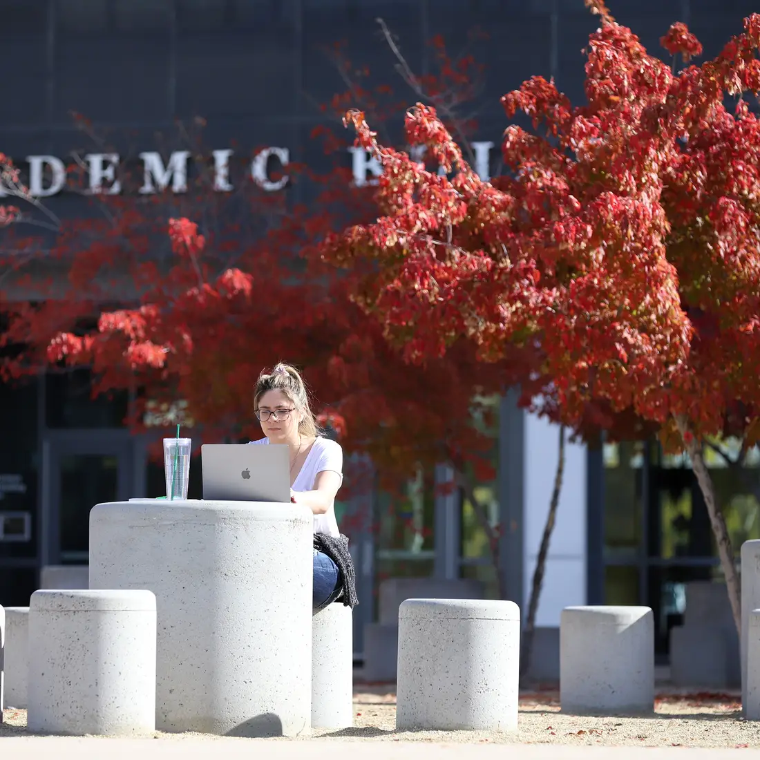 Student studying outside the Nampa Campus Academic Building in the fall