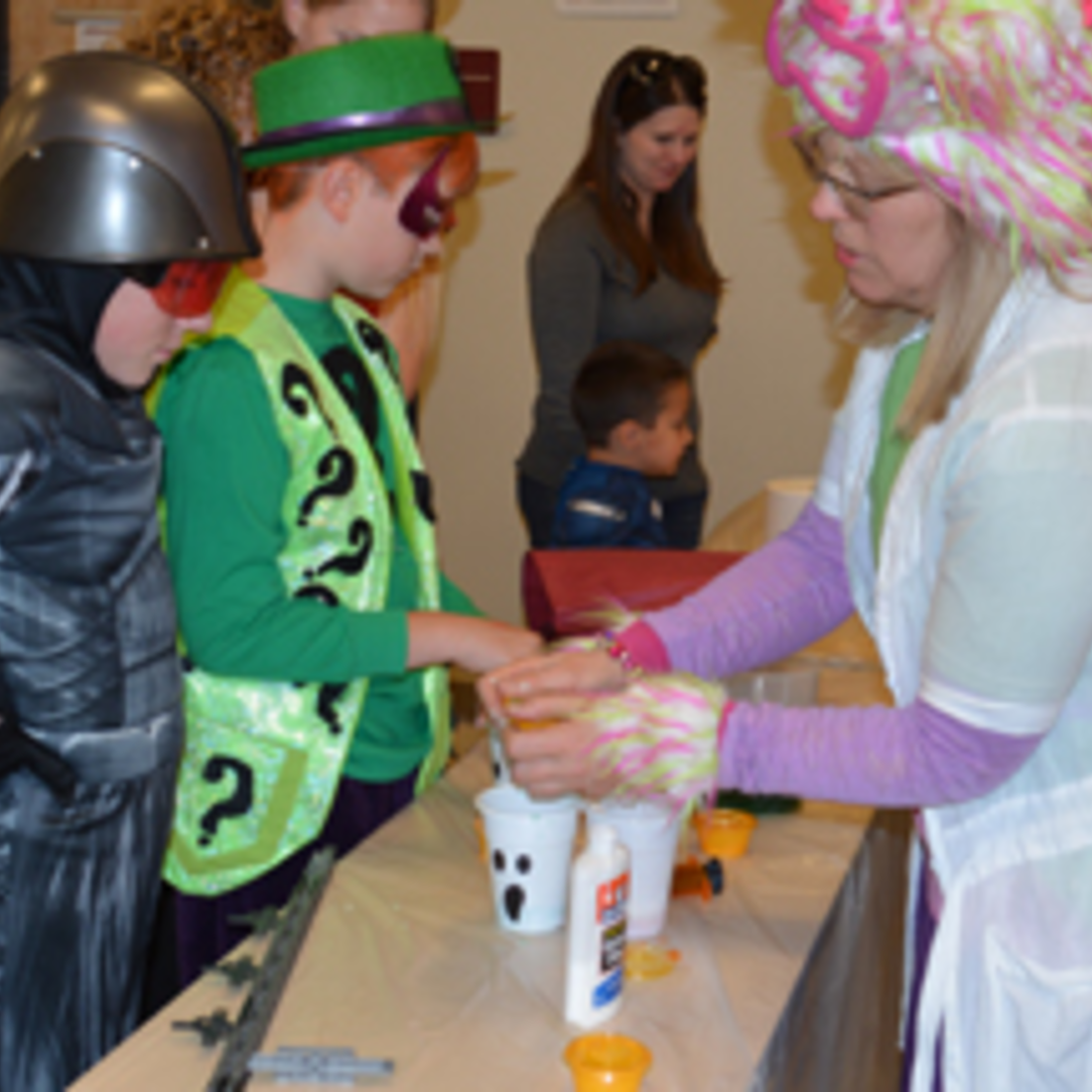 Students handing helping kids with Halloween craft