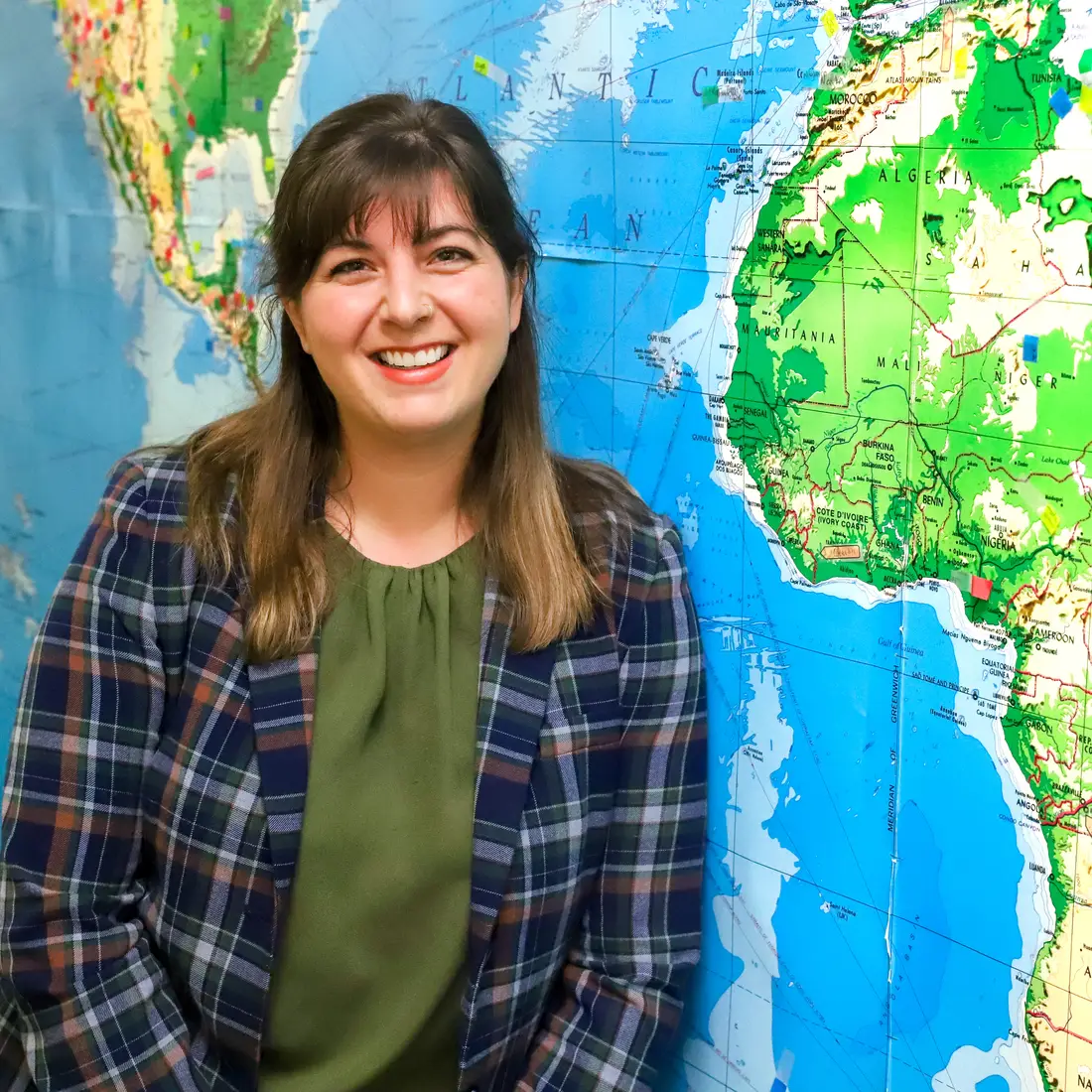 Sarah Strickley leaning against map of world 