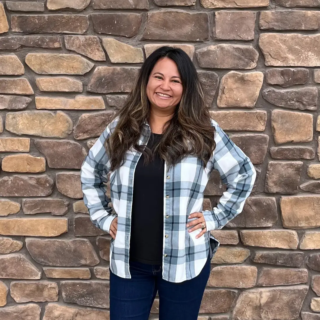 A photo of a woman standing in front of a stone wall.