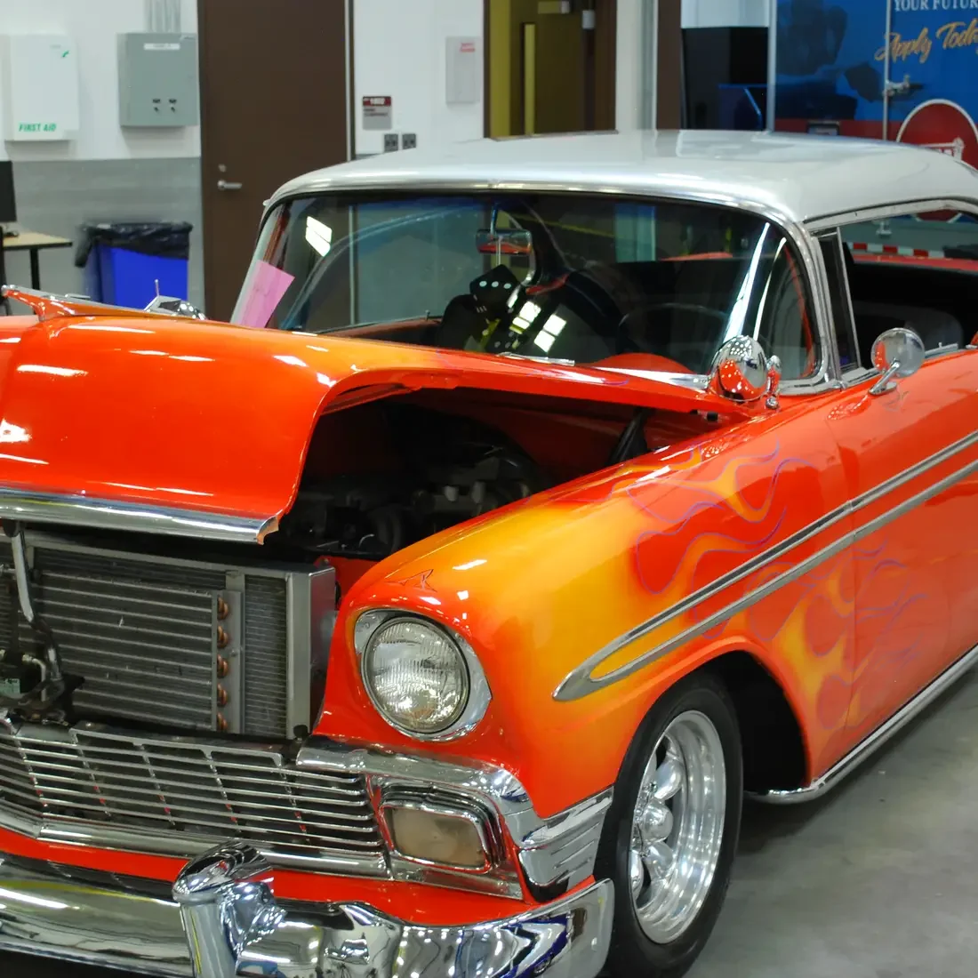 Red Antique car with yellow-orange flames and white top.