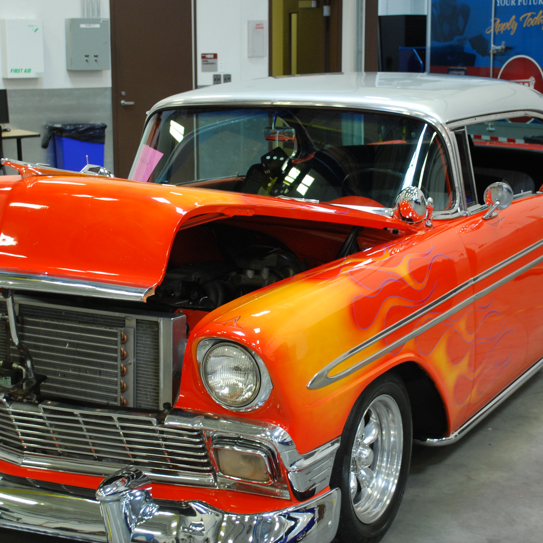 Red Antique car with yellow-orange flames and white top.