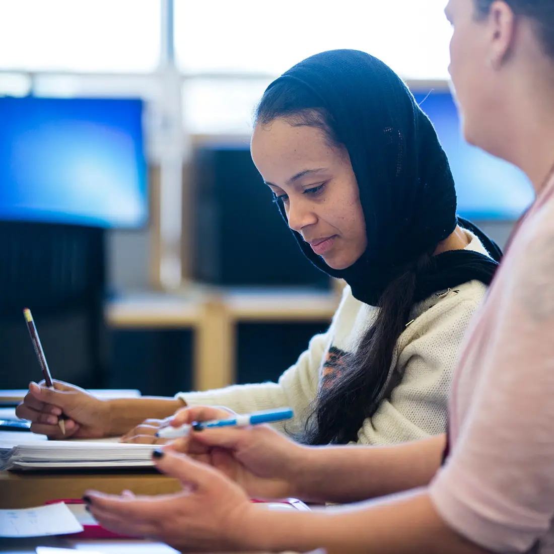 A student receives tutoring at a desk.