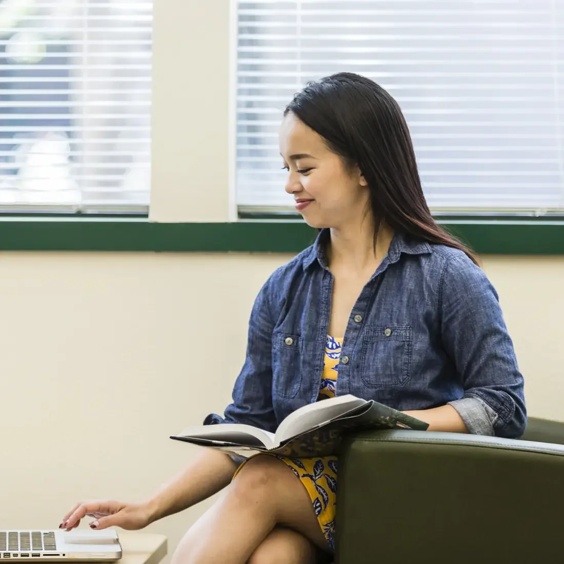 Student sitting with a book and laptop