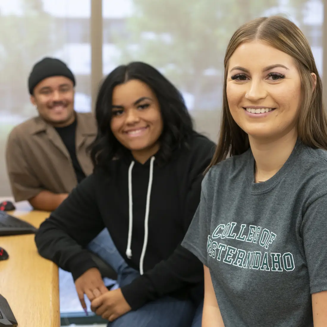Three students sitting at computers in a classroom