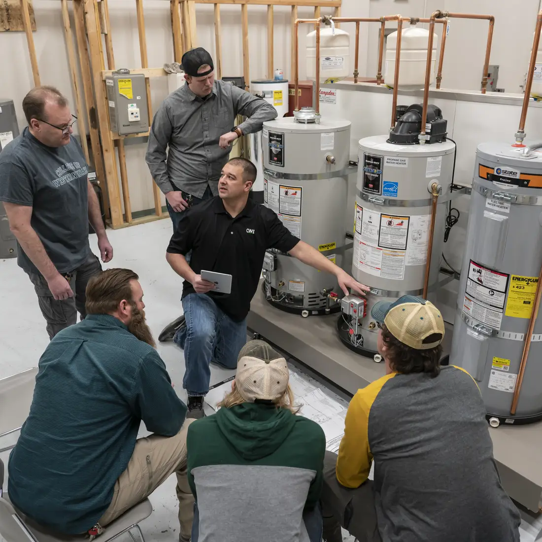 Five students listening to plumbing instructor explain lesson
