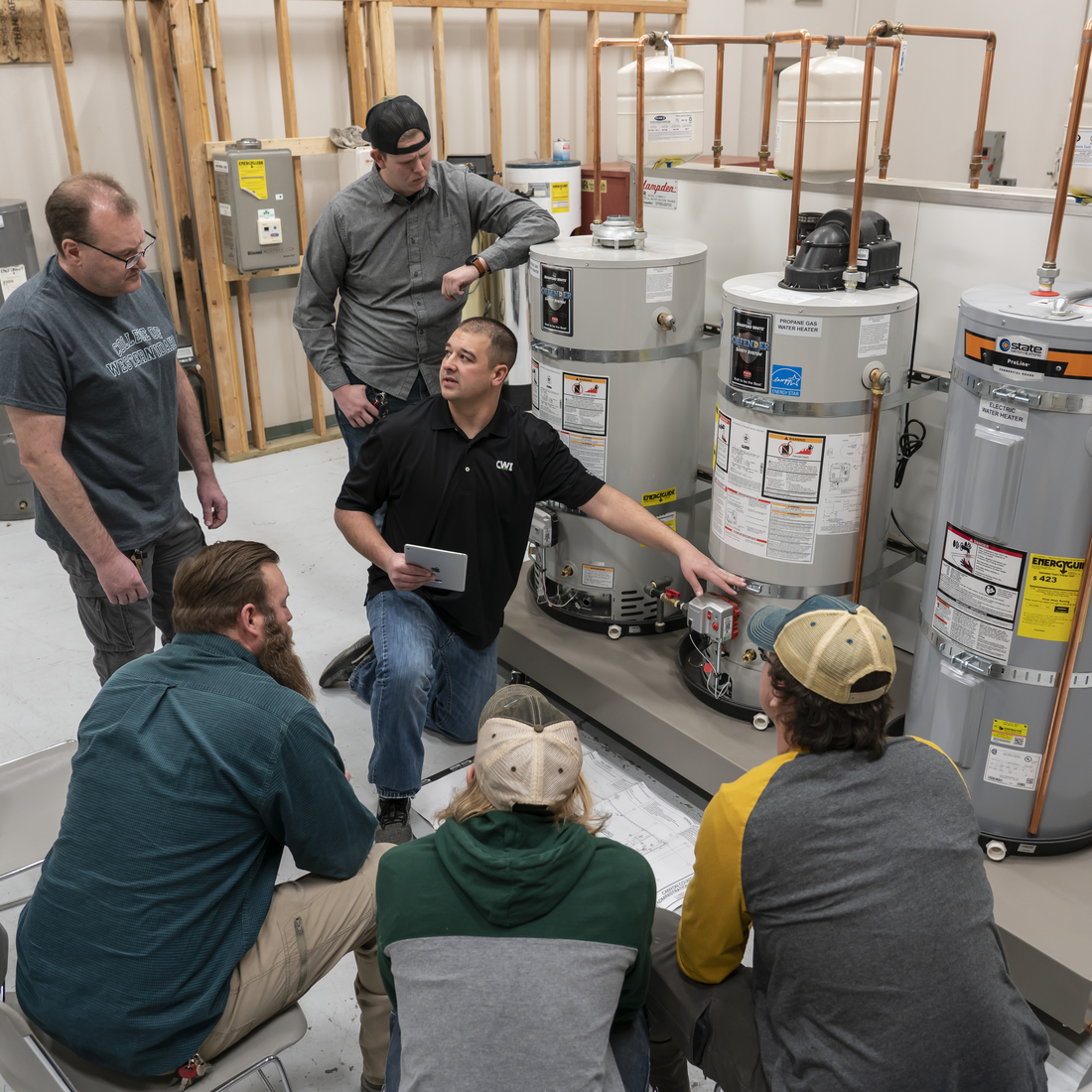 Five students listening to plumbing instructor explain lesson