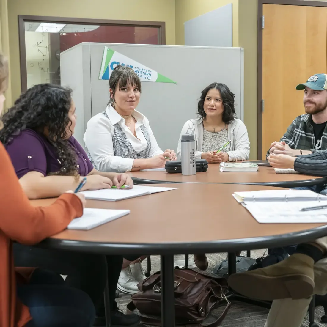 Students and instructors sitting around a table chatting