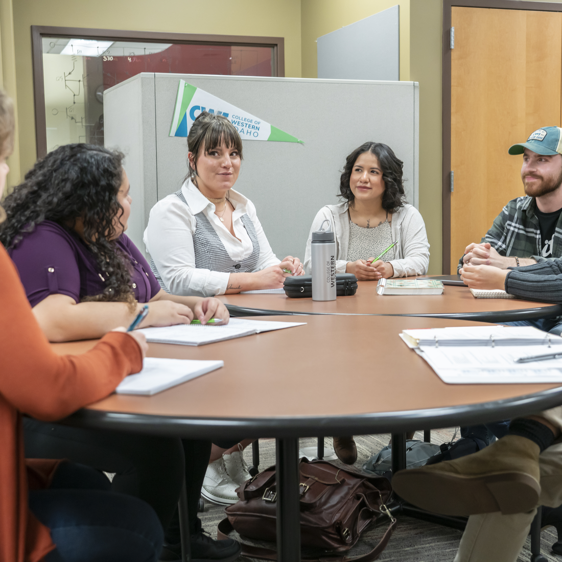 Students and instructors sitting around a table chatting