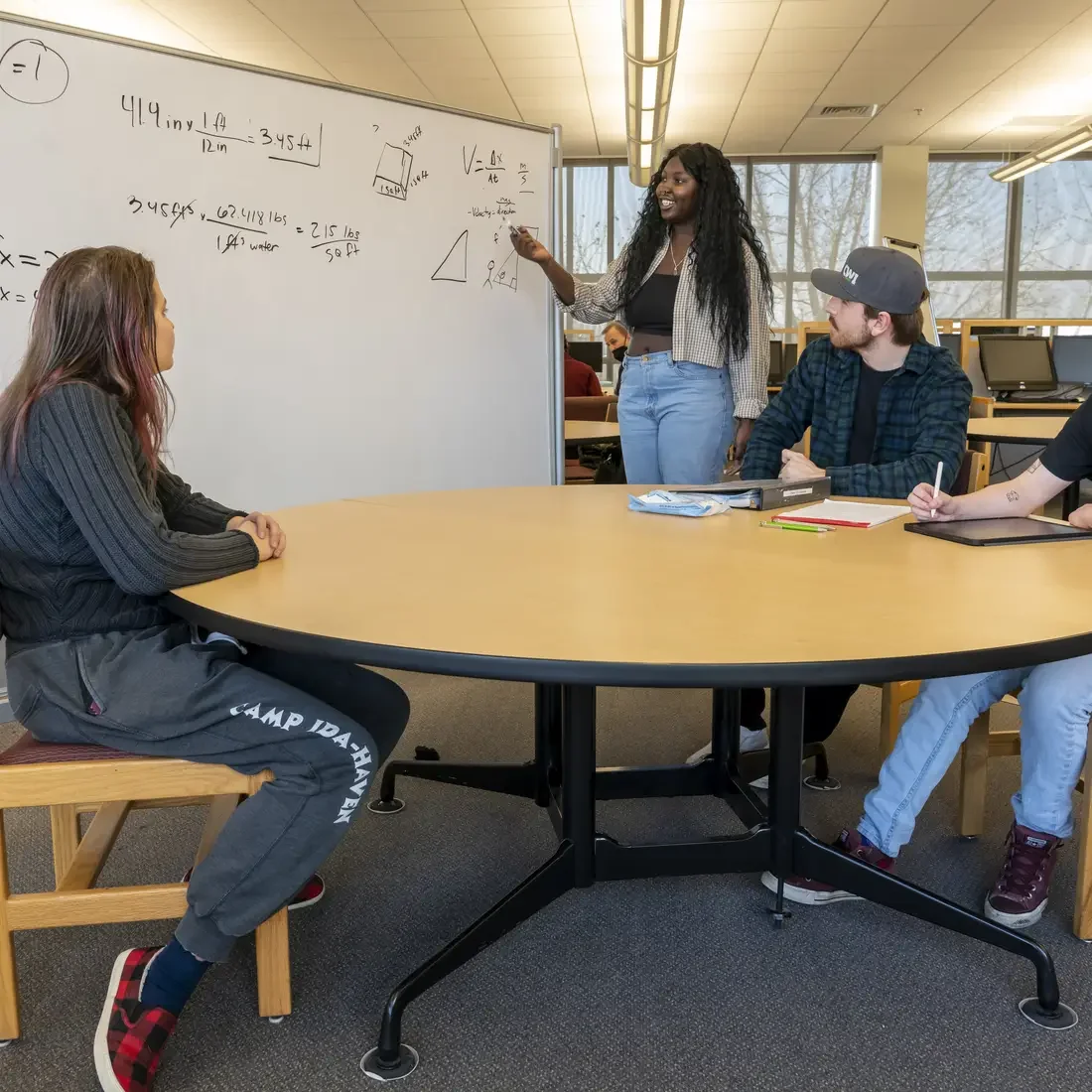 Tutor helping students with math using a whiteboard