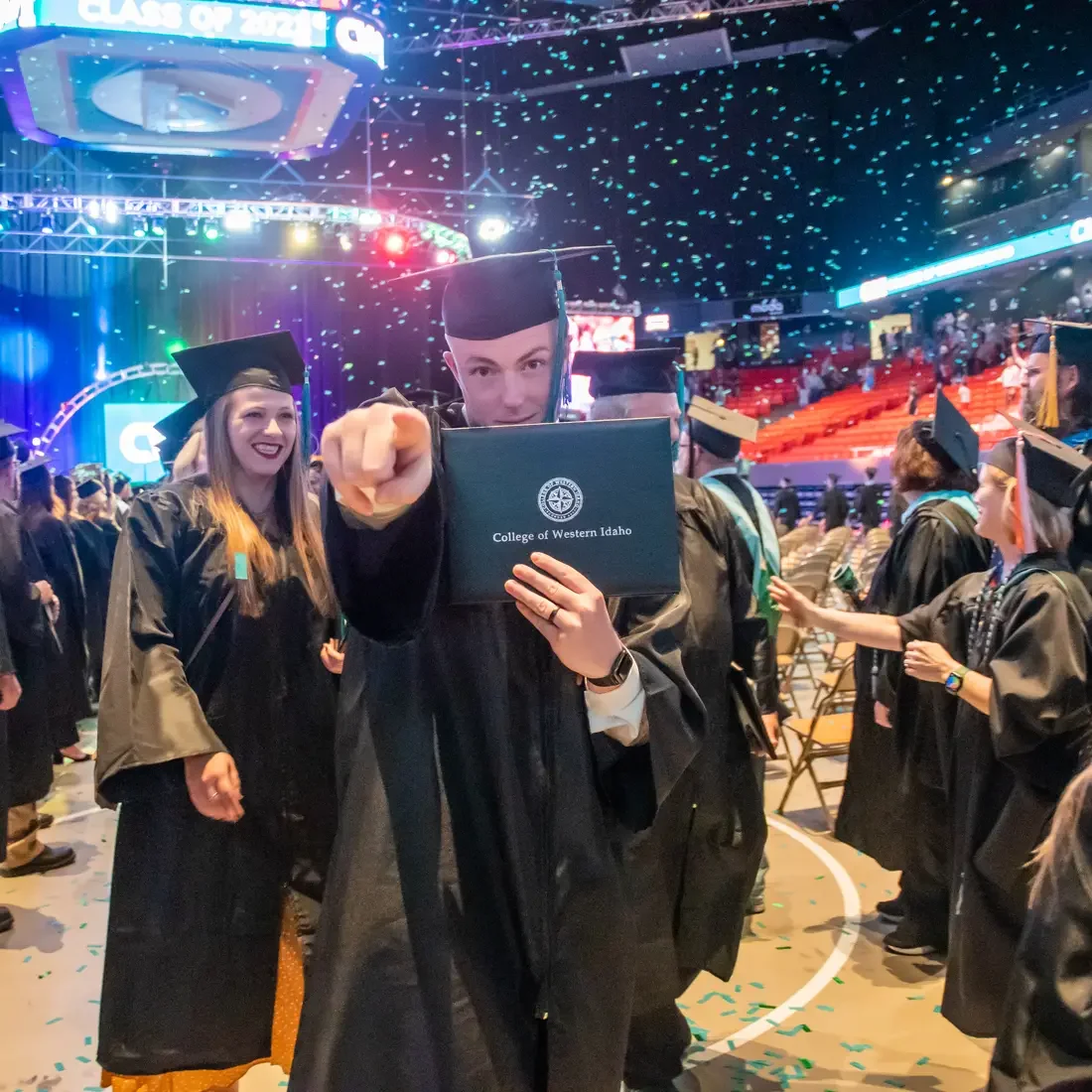 Graduate holding degree and pointing at camera