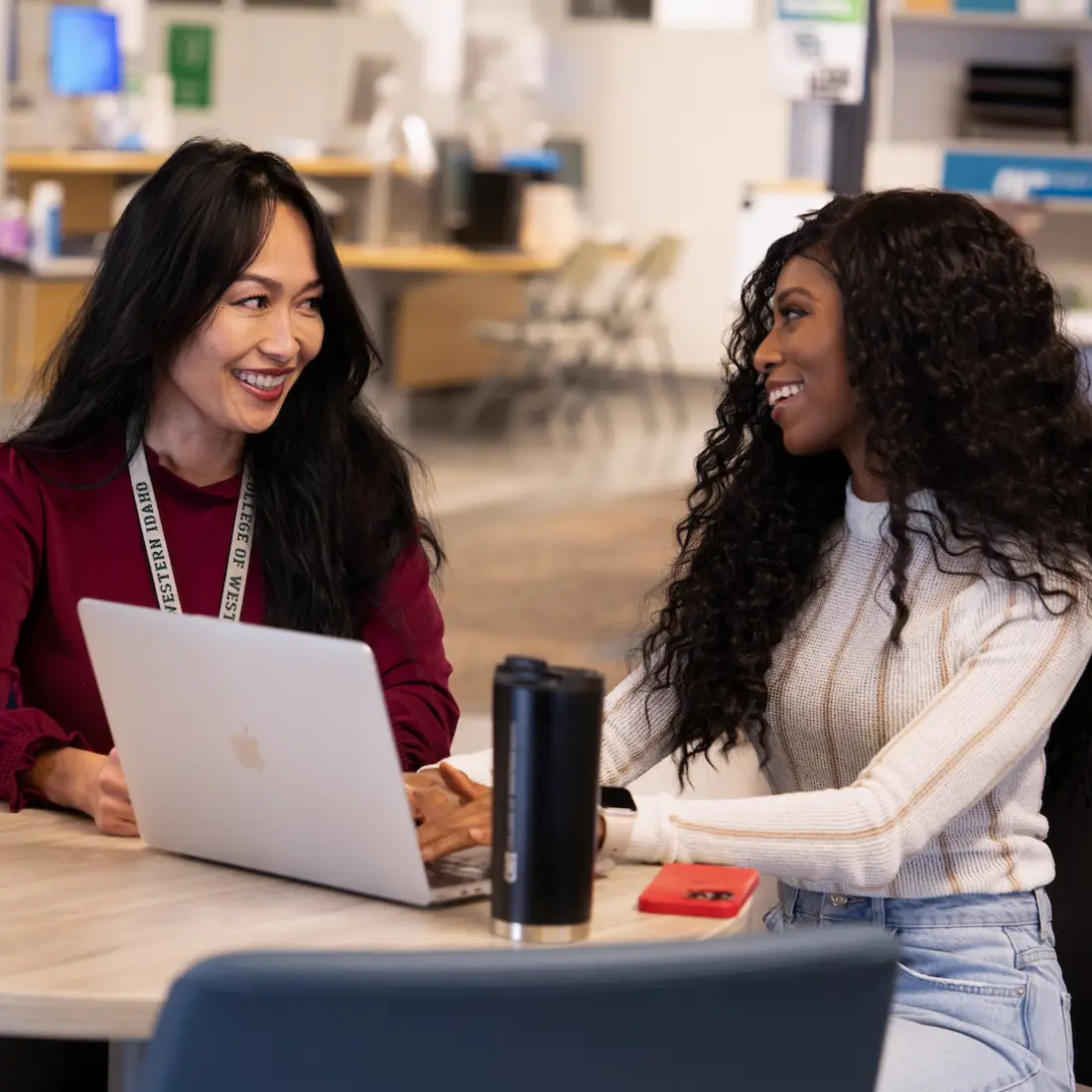 Two people smiling with one on a laptop