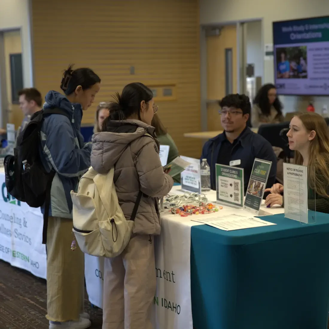 Students speaking with staff at a table