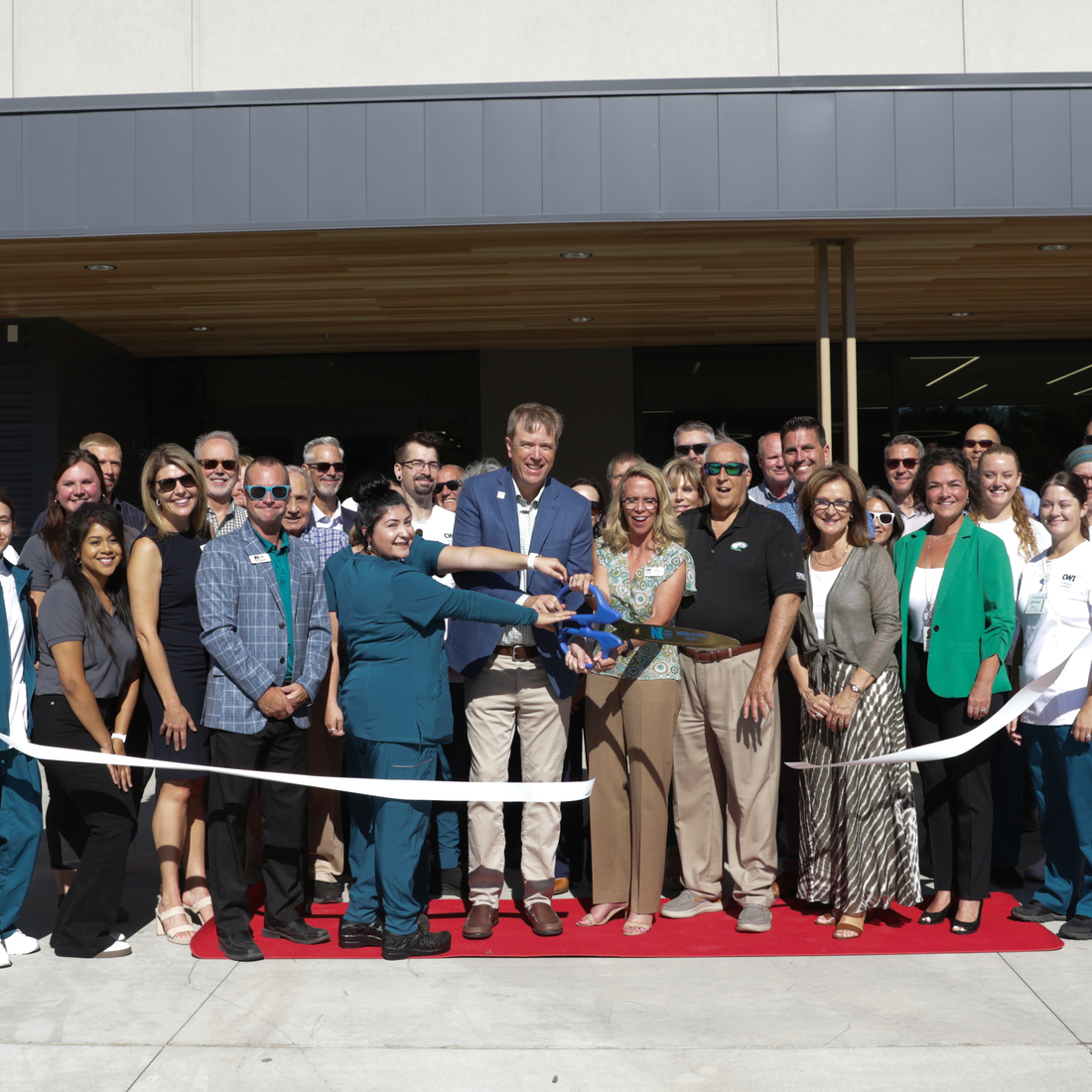 Large group of people cutting a ribbon
