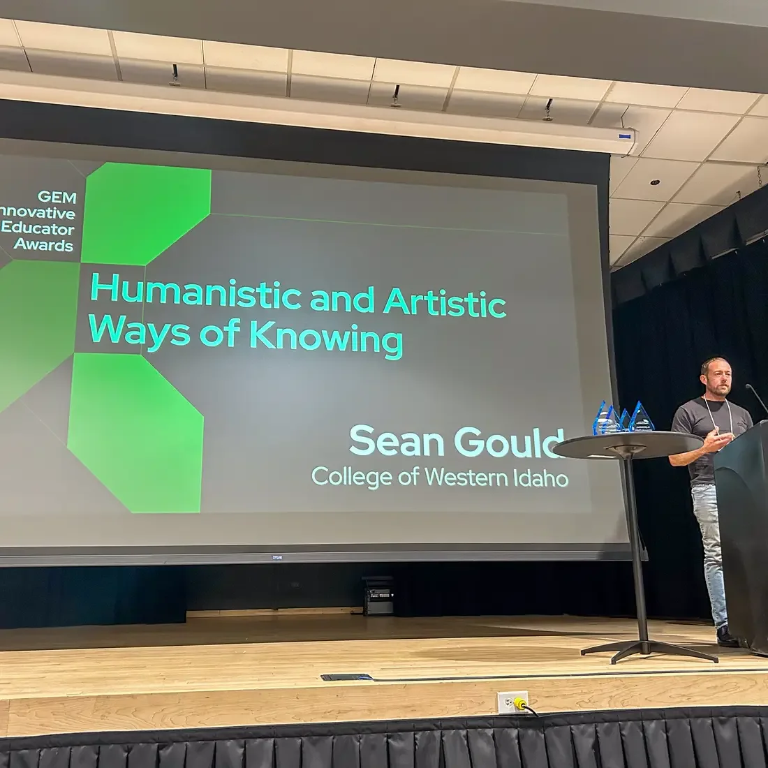 Sean Gould presenting on stage with projector screen behind them