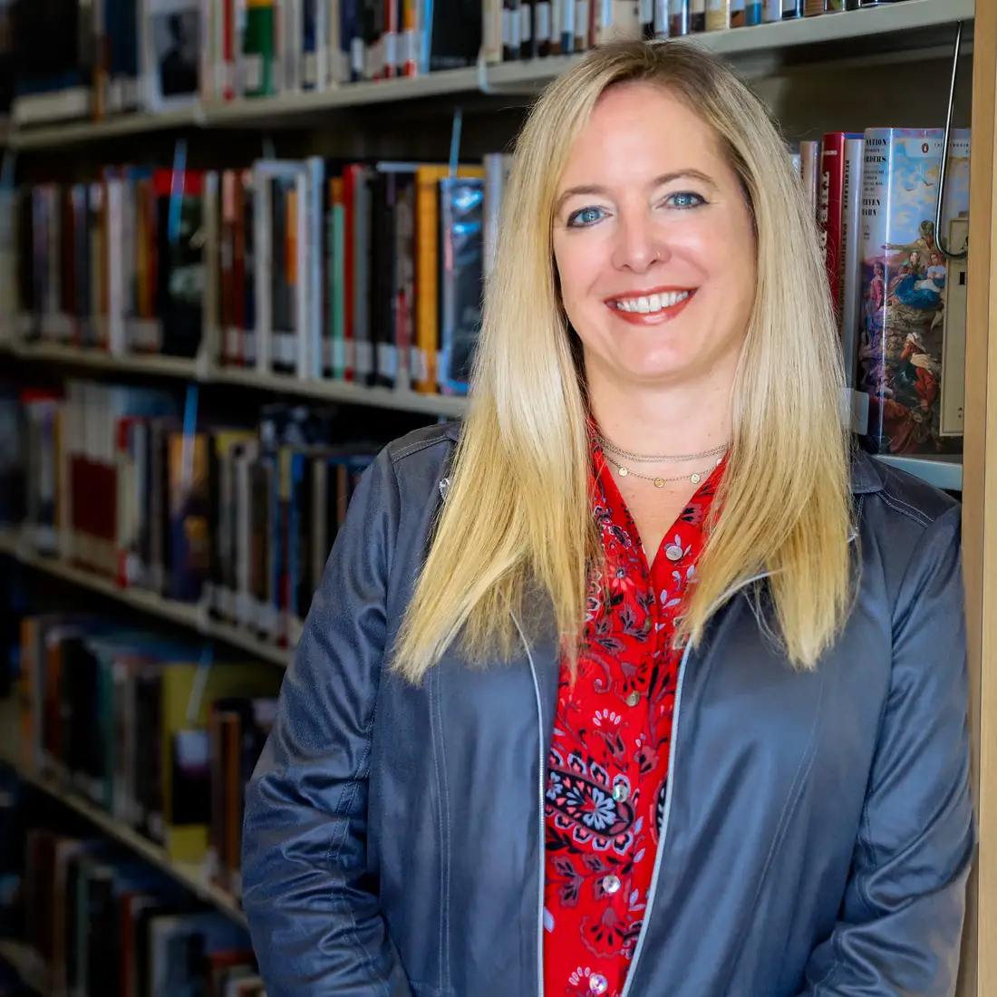Kim Reed leaning against a bookshelf