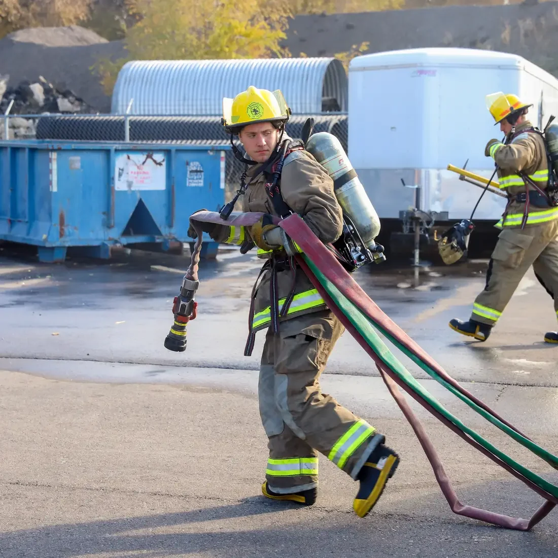 Fire student carrying hose