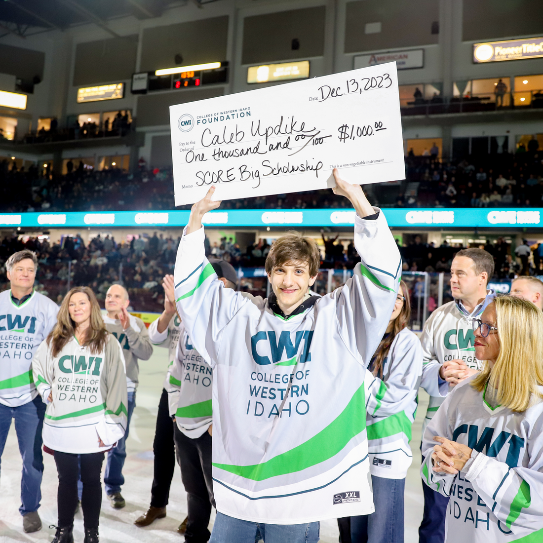 Caleb Updike holding a scholarship check.