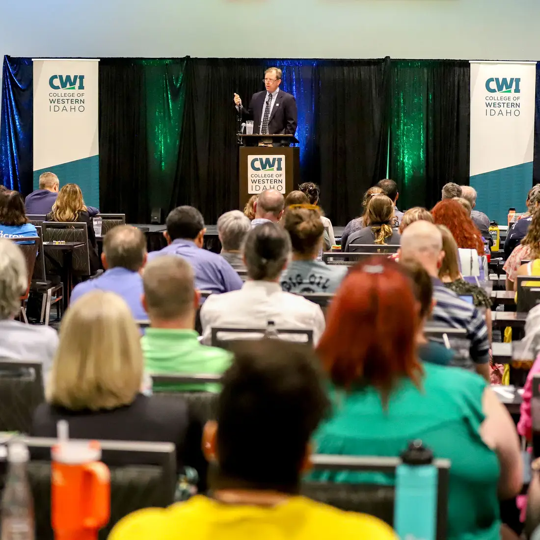 Faculty and staff sit and listen to a speaker addressing the room.