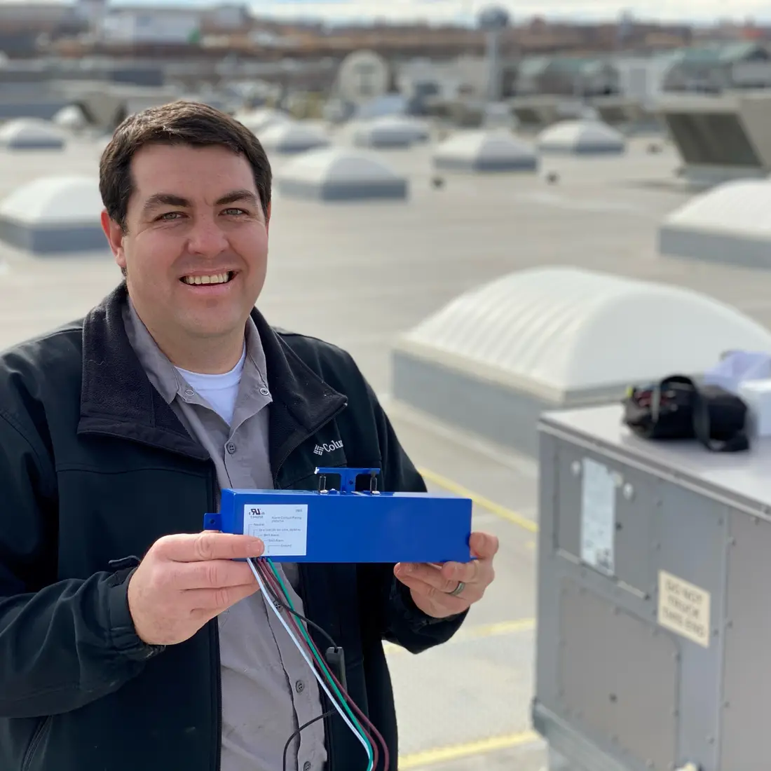 Brandon Martinez, Facilities HVAC Mechanic, holds a compact self-cleaning ionization system 