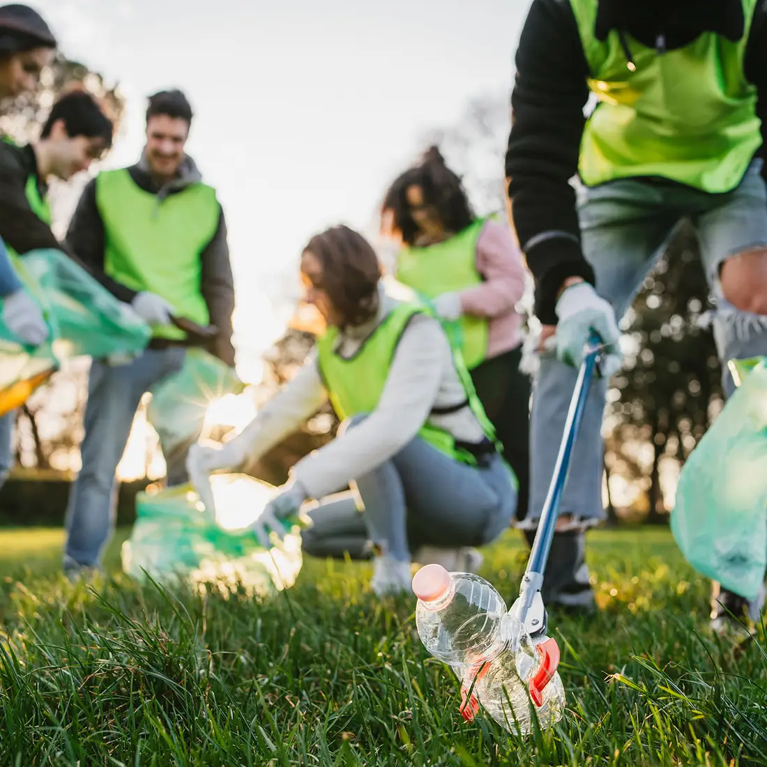 Students volunteer in a park by picking up trash.