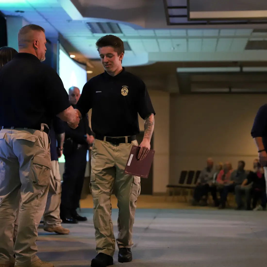 Student walking across the stage shaking hands with leadership