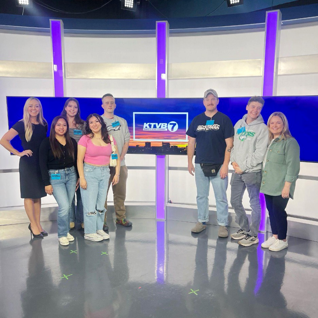 Students touring a TV news station pose for a photo on set. 
