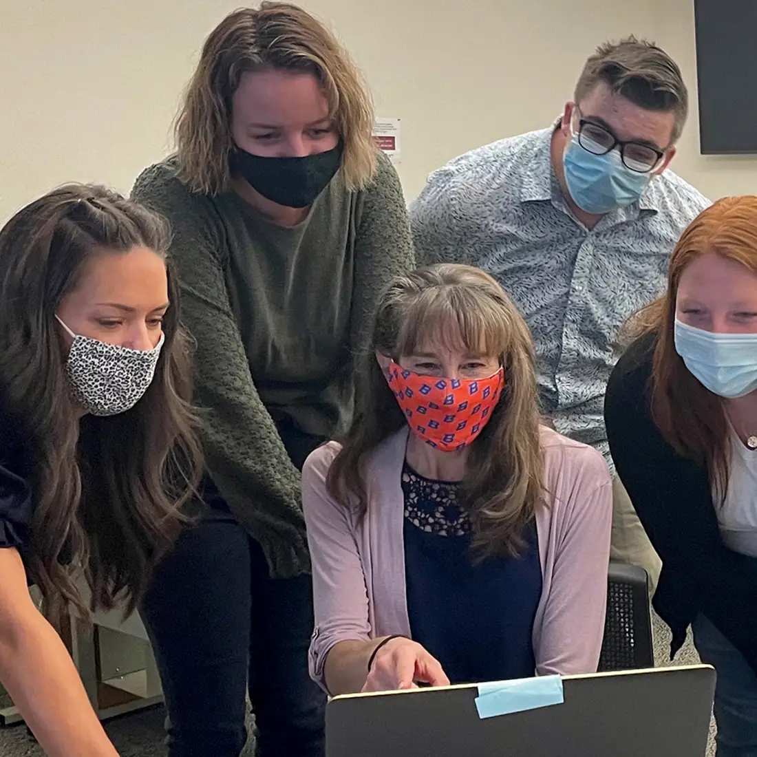 Psychology students and professors working together at a laptop