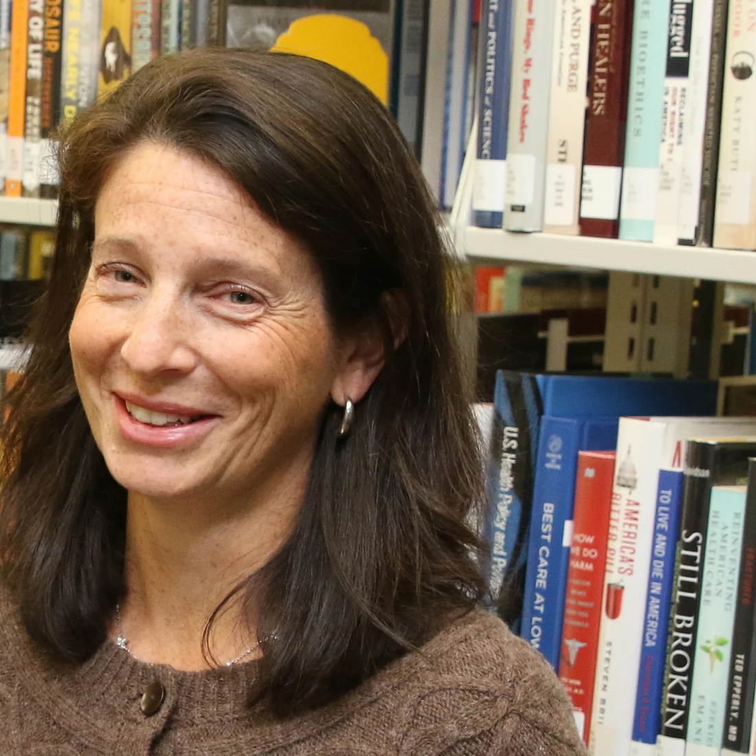 A professor poses for a photo in a library.