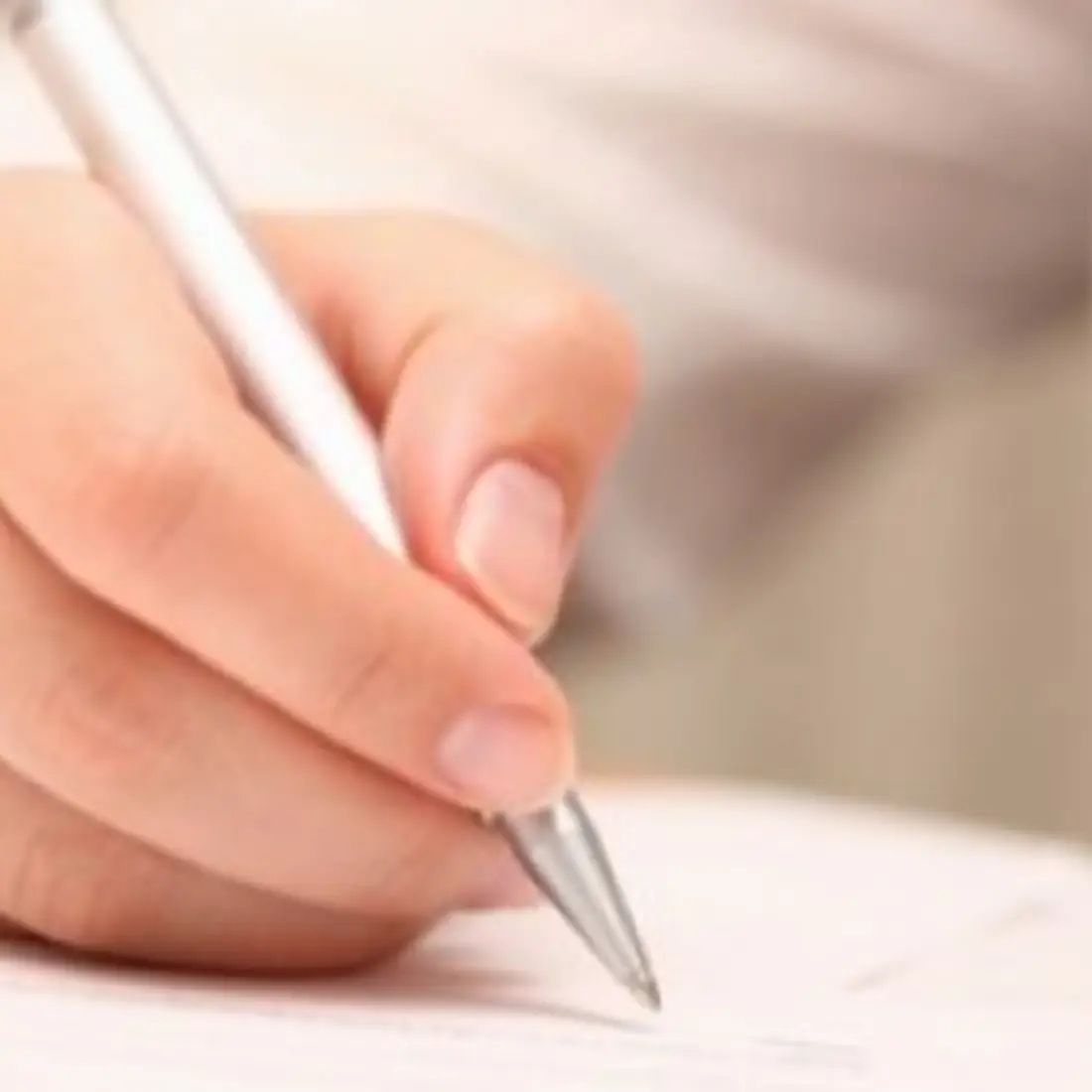 Close up of hands over paper with pen in right hand.