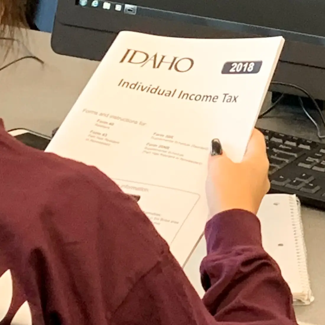 Volunteer Income Tax Assistance Program volunteer holding 2018 tax guidelines