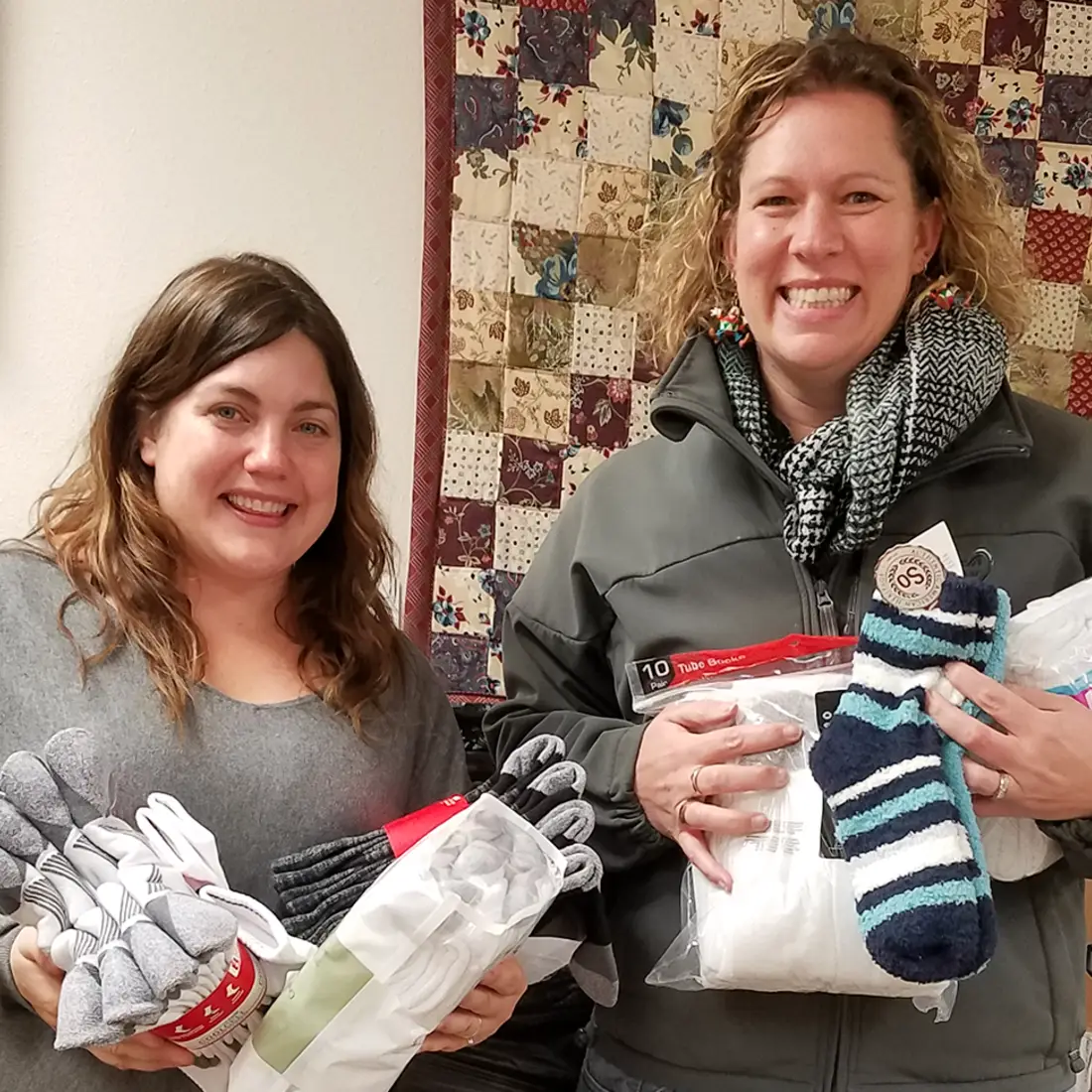 Two women holding sock donations. 