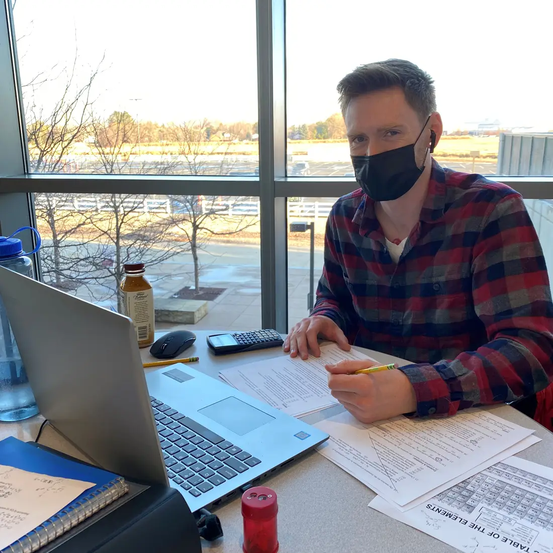 Student wearing a mask studying on campus on a laptop