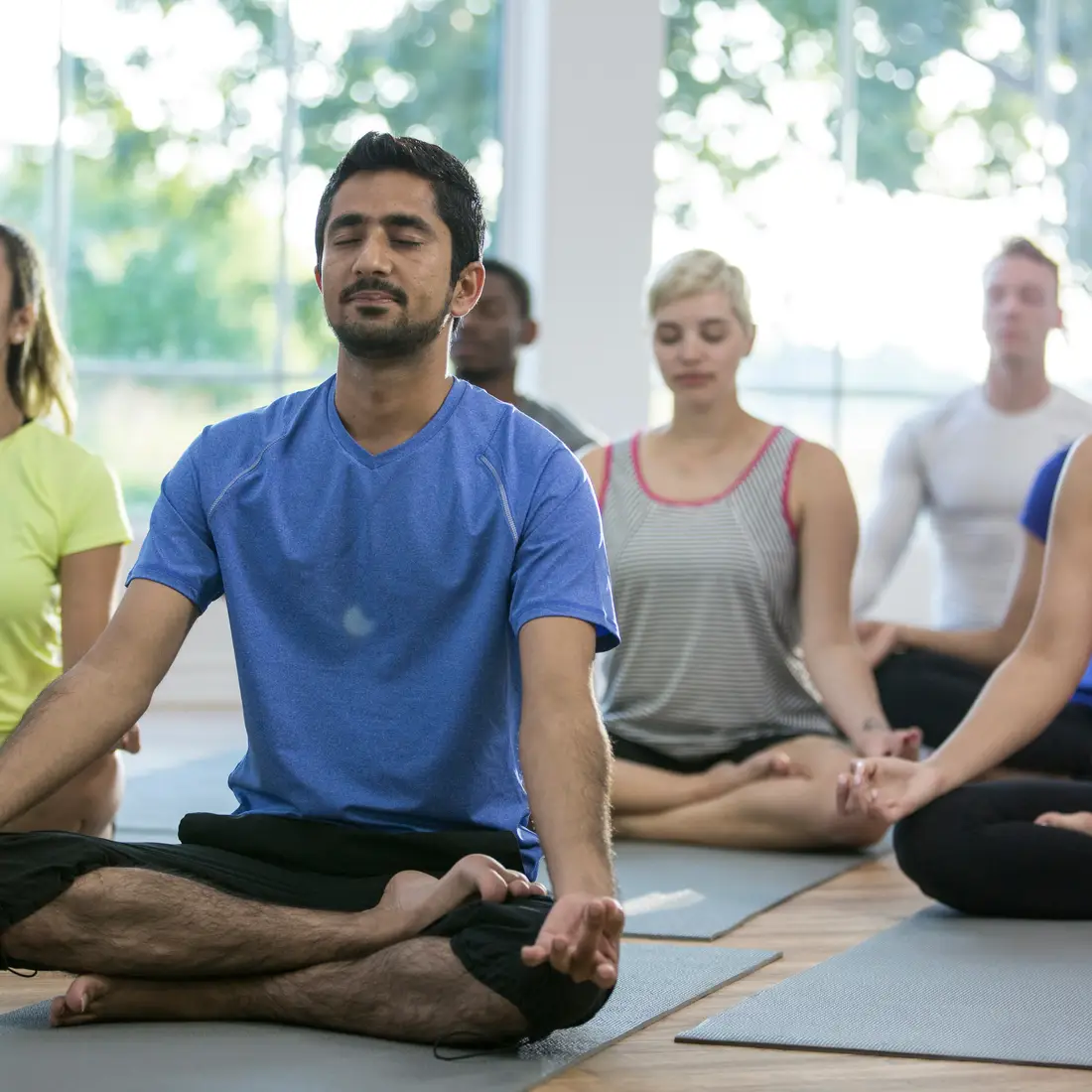Class of yoga students seated with their eyes closed