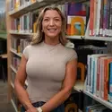Amy Miller stands in front of a library bookcase