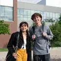 Two students with bags standing outside building