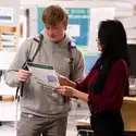 Staff helping a student showing them something on a flyer
