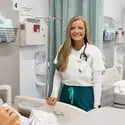 Jessica Smith stands next to a hospital bed with a mannequin