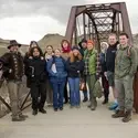 Group of people stand in front of a bridge