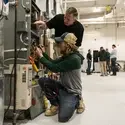 Instructor and student work on HVAC unit in lab