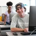Student at a desk with several other student behind him