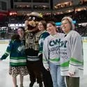 People and mascot stand on ice