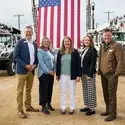 Five people stand in front of an American Flag