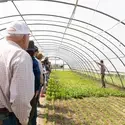 Group of people standing in greenhouse listening to tour guide