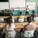 Students in a classroom with an instructor teaching at the front of the classroom
