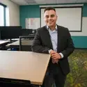 Ismael Garcia stands in front of desk in a classroom