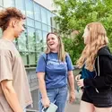 Three students stand near railing and laughing